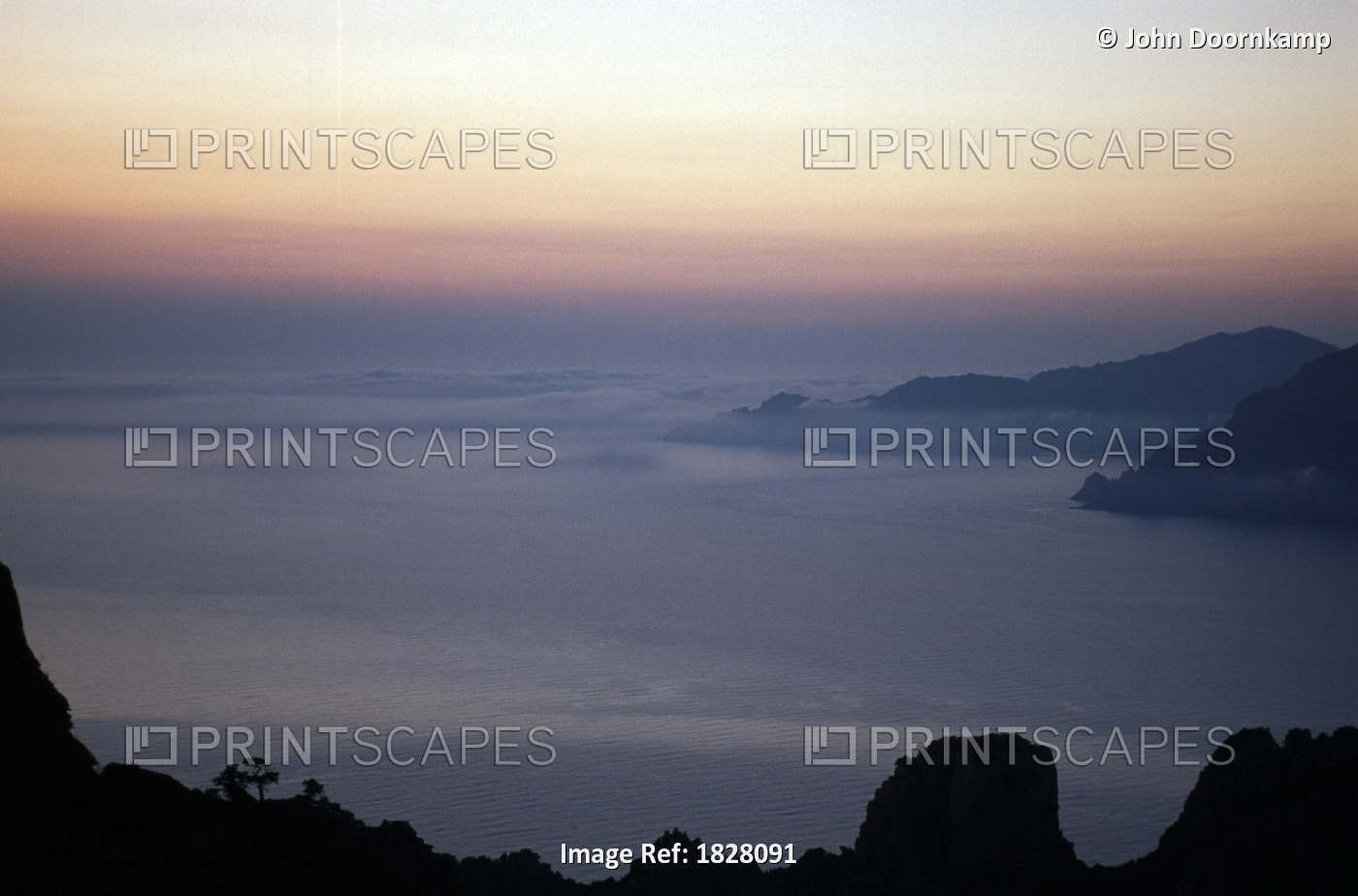 CORSICA, FRANCE; HIGH ANGLE VIEW OF SUNSET ON THE FOG COVERED COAST