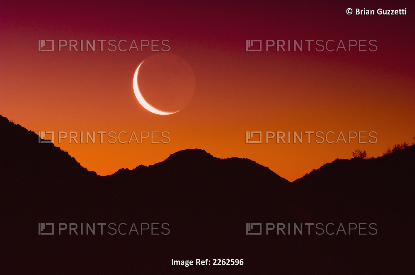 Sunrise over a mountain range in joshua tree national park with the moon in the ...