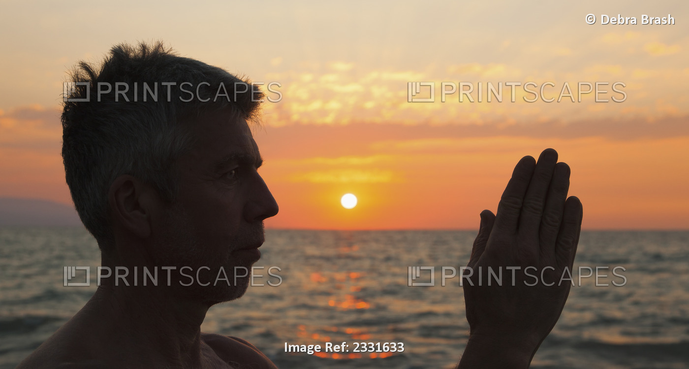 A man in prayer or yoga pose as the sun set on a tropical beach;Puerto vallarta ...