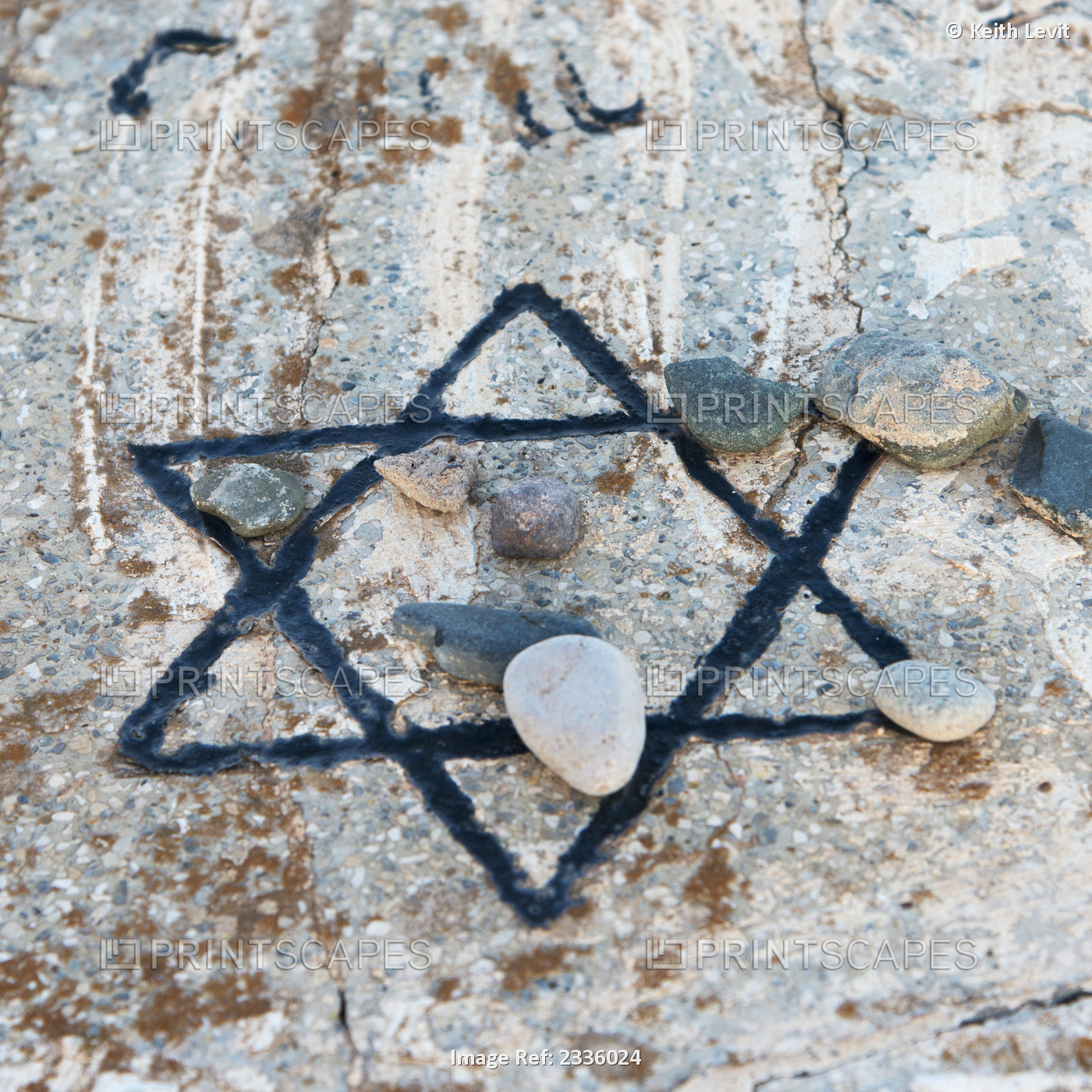 A star of david etched and painted on a rock with stones laying on it