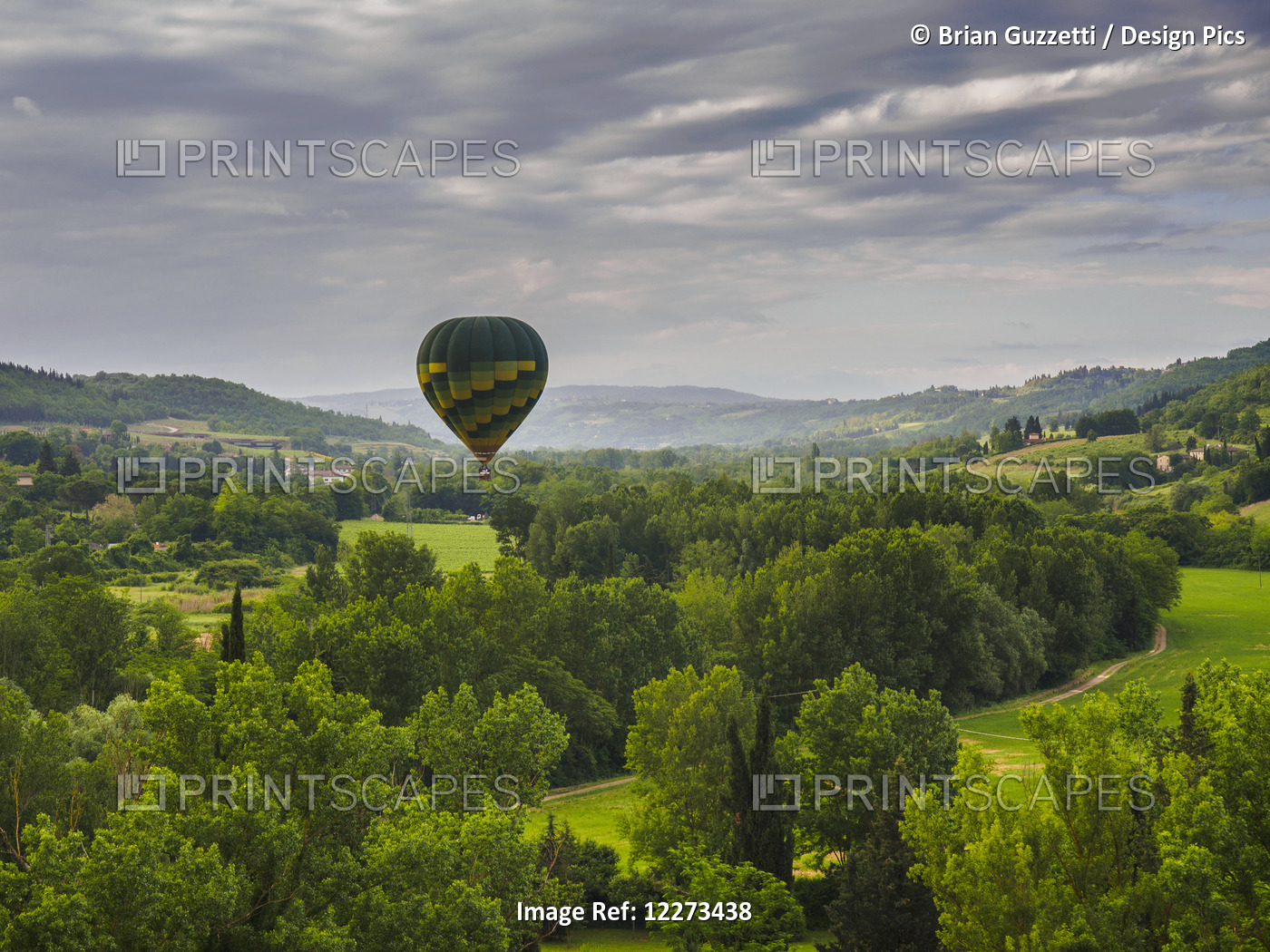 A Hot Air Balloon Flies Low Over A Spring Valley Landscape; Tuscany, Italy