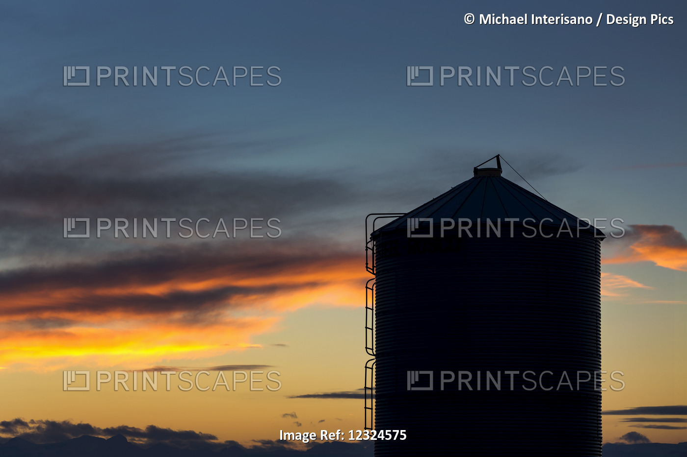 Silhouette Of Large Metal Grain Bin With Colourful Clouds At Sunset With Blue ...