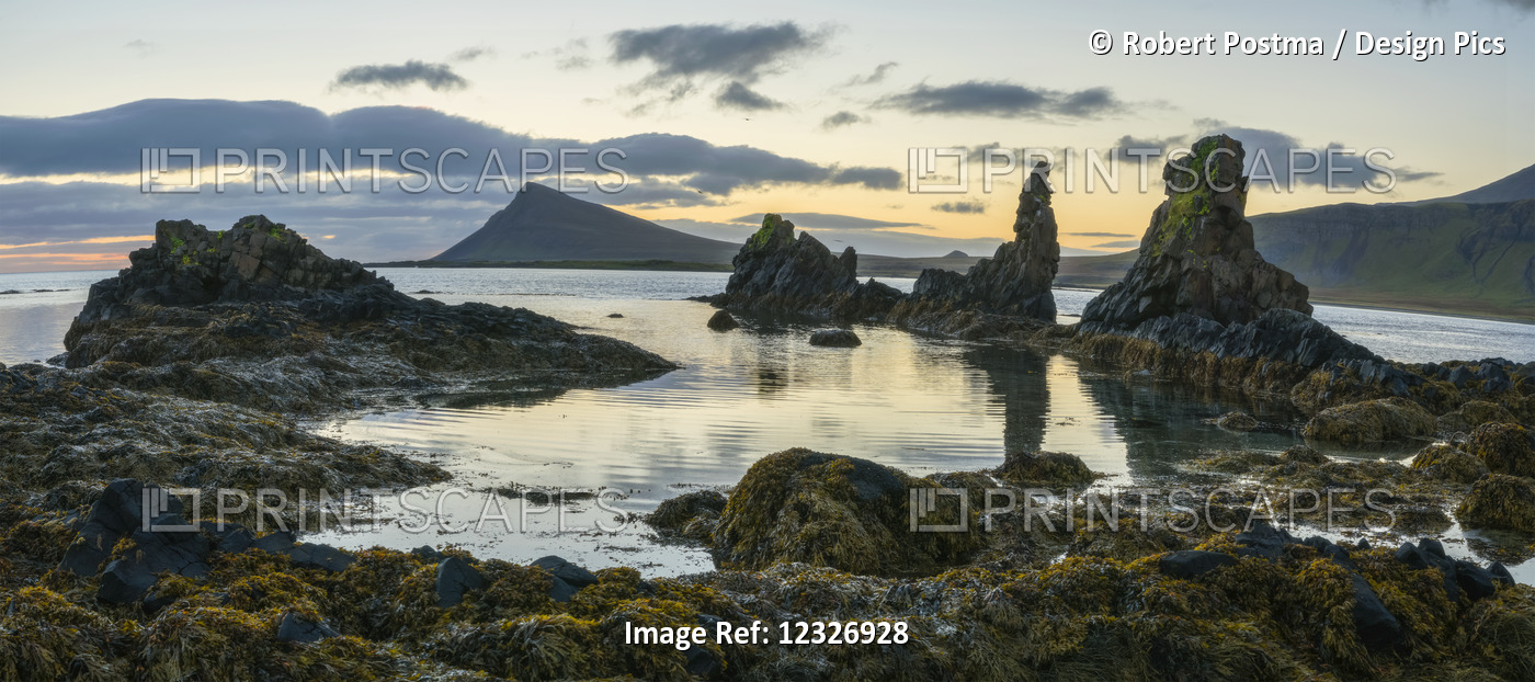 Sunrise Over Some Lava Pillars With A Large Sea Cliff Rising In The Horizon, ...
