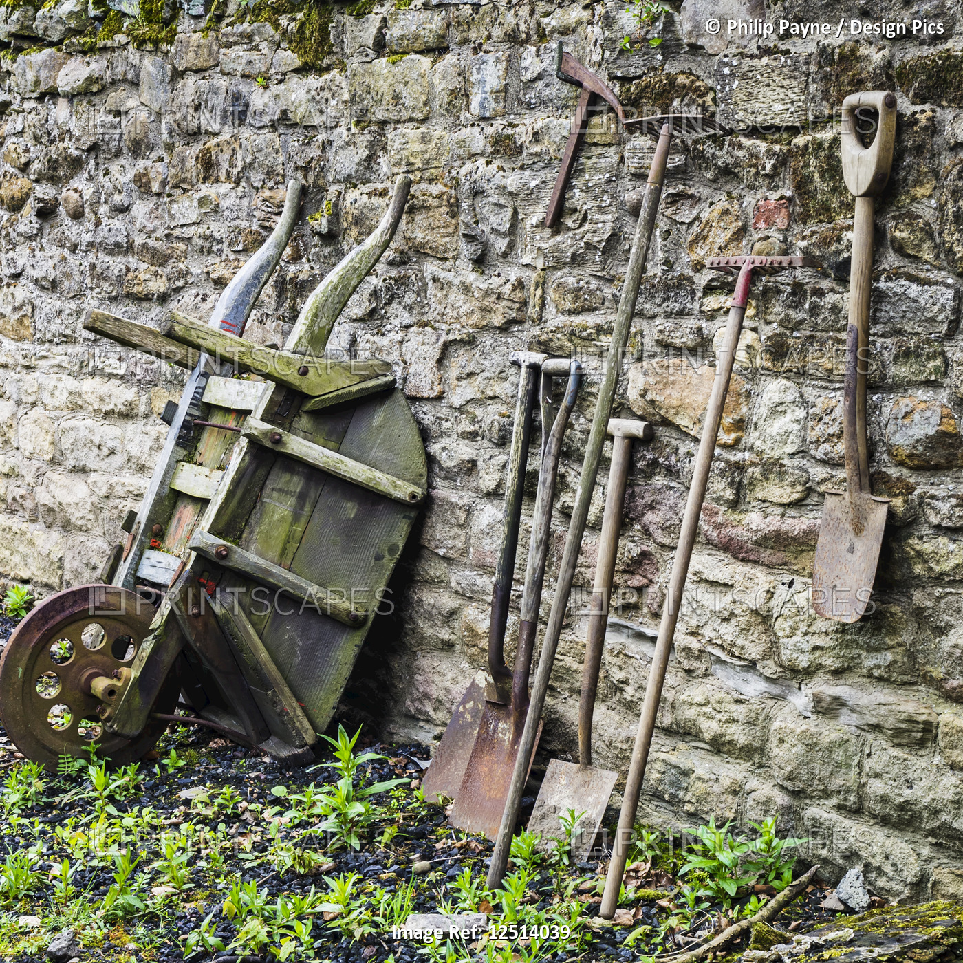 Old garden tools leaning up against a weathered stone wall, Open Air Museum, ...