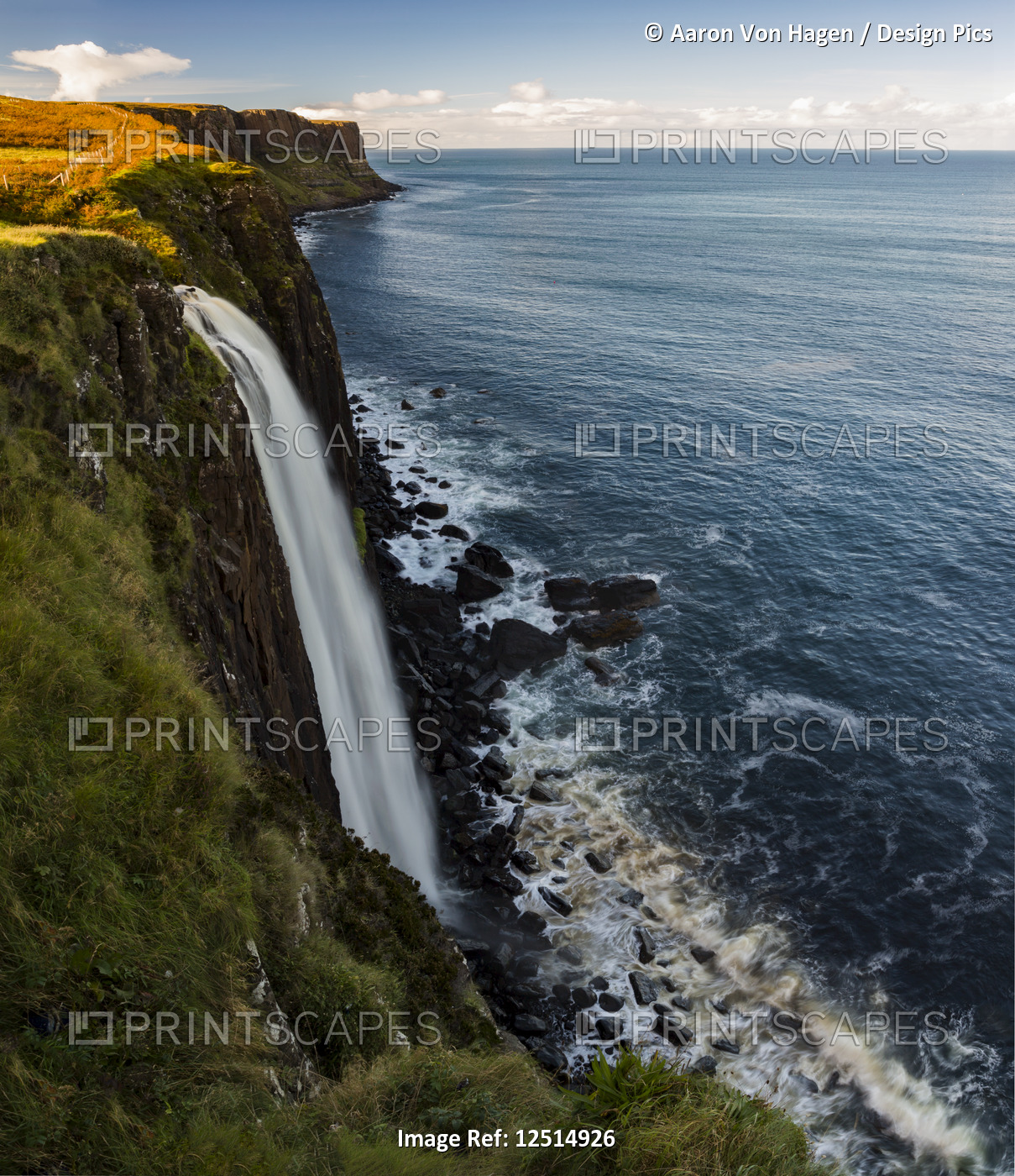 A waterfall flowing over a cliff along the coastline; Isle of Skye, Scotland