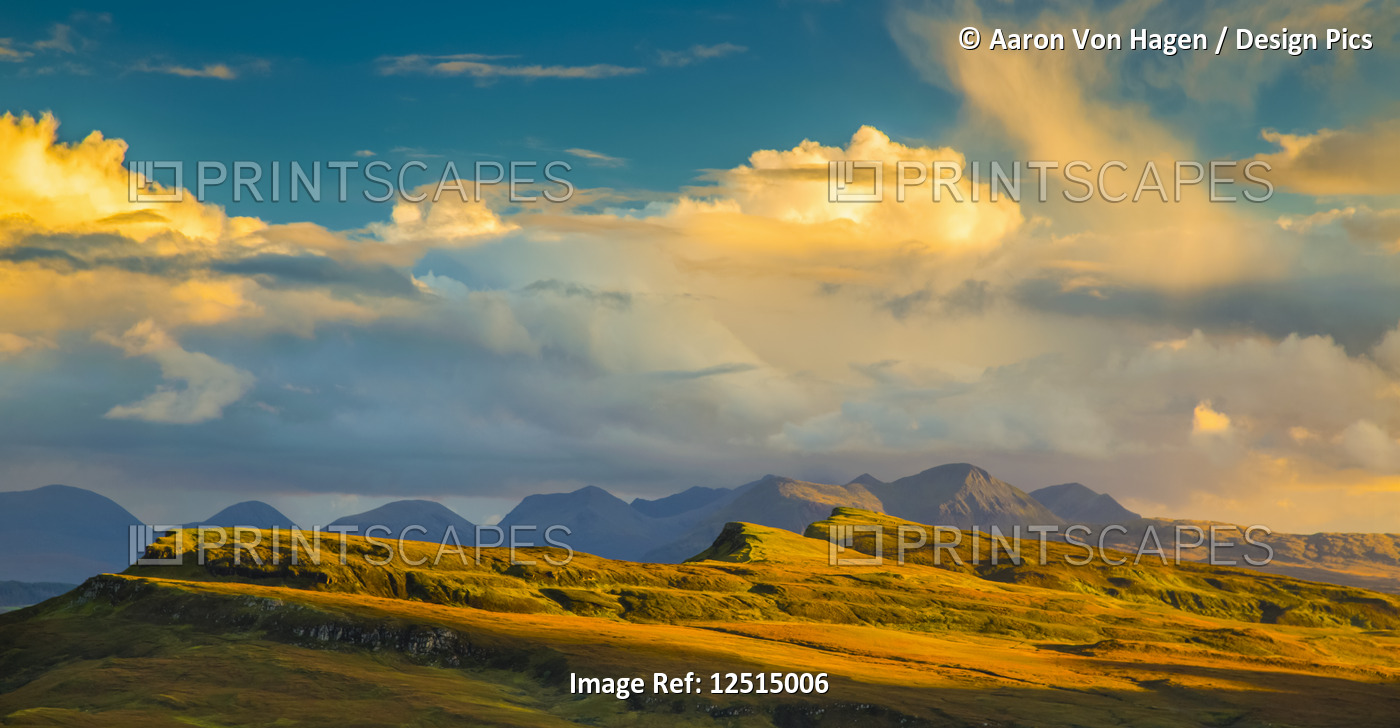 Sunlight illuminating the mountainous landscape and clouds; Isle of Skye, ...
